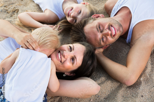 family lying on beach, top view.