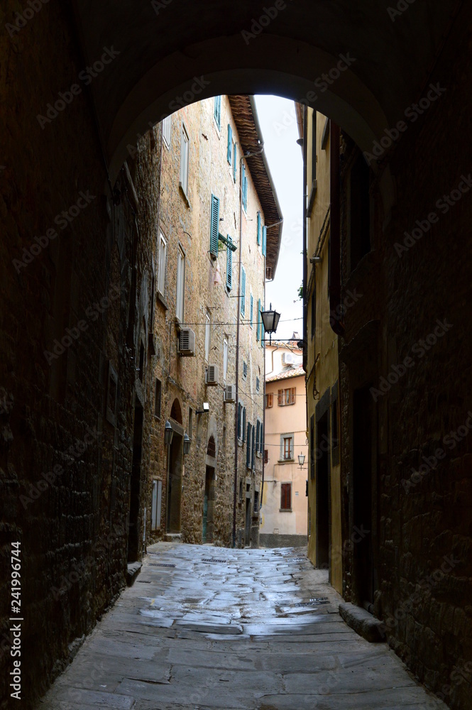 Narrow alley in italian old town seen through the arch