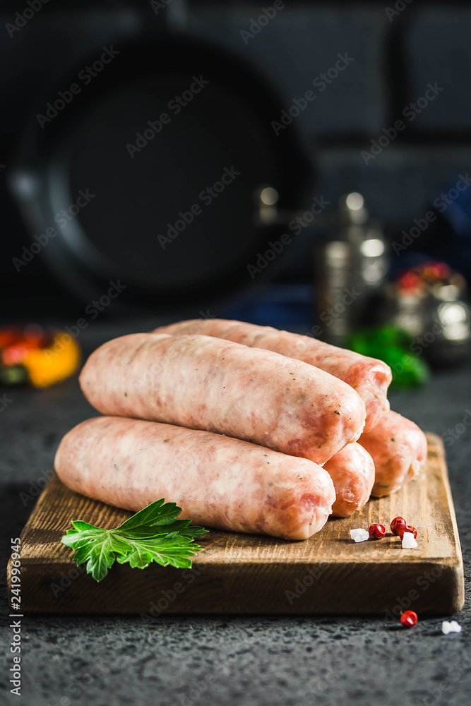 Raw sausages with herbs, spices, herbs on dark background. Selective focus, space for text.