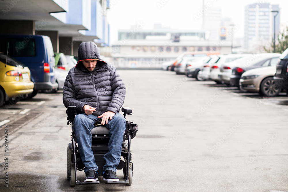 Young, adult wheelchair user on a parking lot with copy space