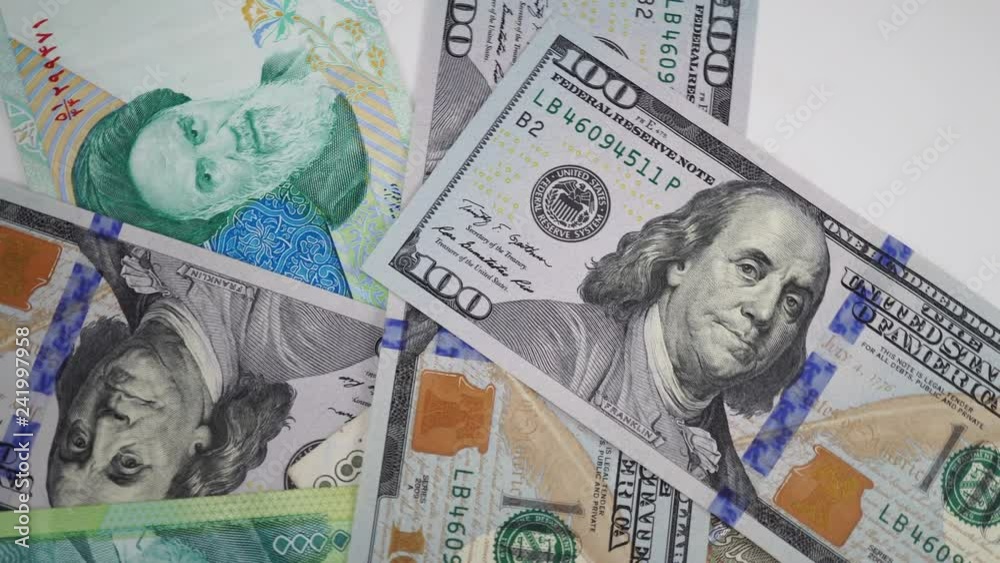 Iranian rial and dollars on rotating table. Portrait of Khomeini on