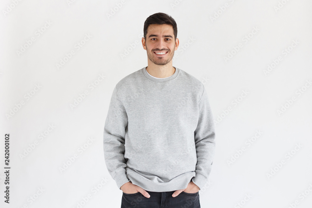 Daylight portrait of young handsome man, wearing oversized sweatshirt, isolated on gray background Daylight portrait of young handsome man, wearing oversized sweatshirt, isolated on gray background