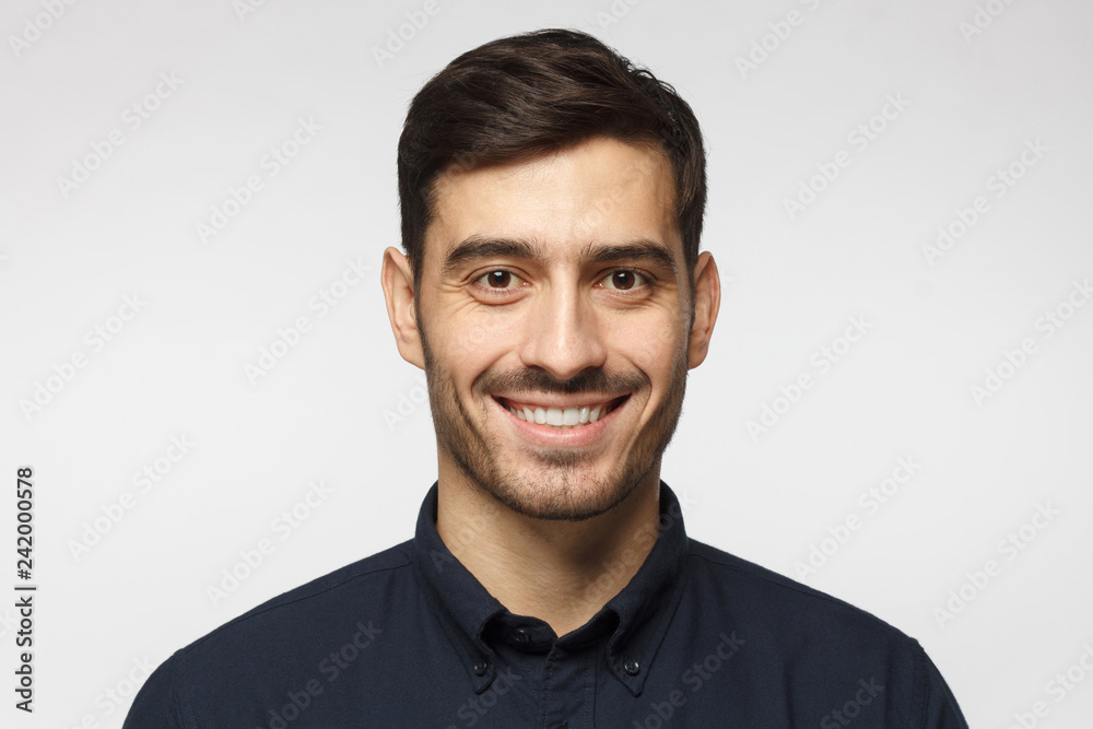 Closeup headshot of business man standing against gray background, smiling with satisfaction and confidence Closeup headshot of business man standing against gray background, smiling with satisfaction and confidence