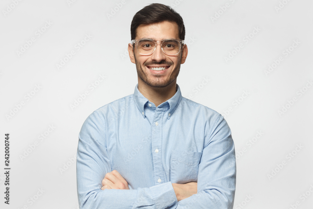 Handsome smiling business man in blue shirt standing with crossed arms, isolated on gray background Handsome smiling business man in blue shirt standing with crossed arms, isolated on gray background