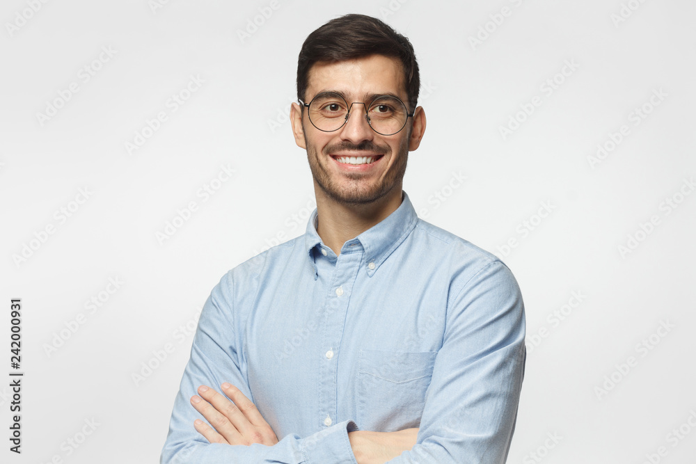 Handsome smiling business man in blue shirt standing with crossed arms, isolated on gray background Handsome smiling business man in blue shirt standing with crossed arms, isolated on gray background
