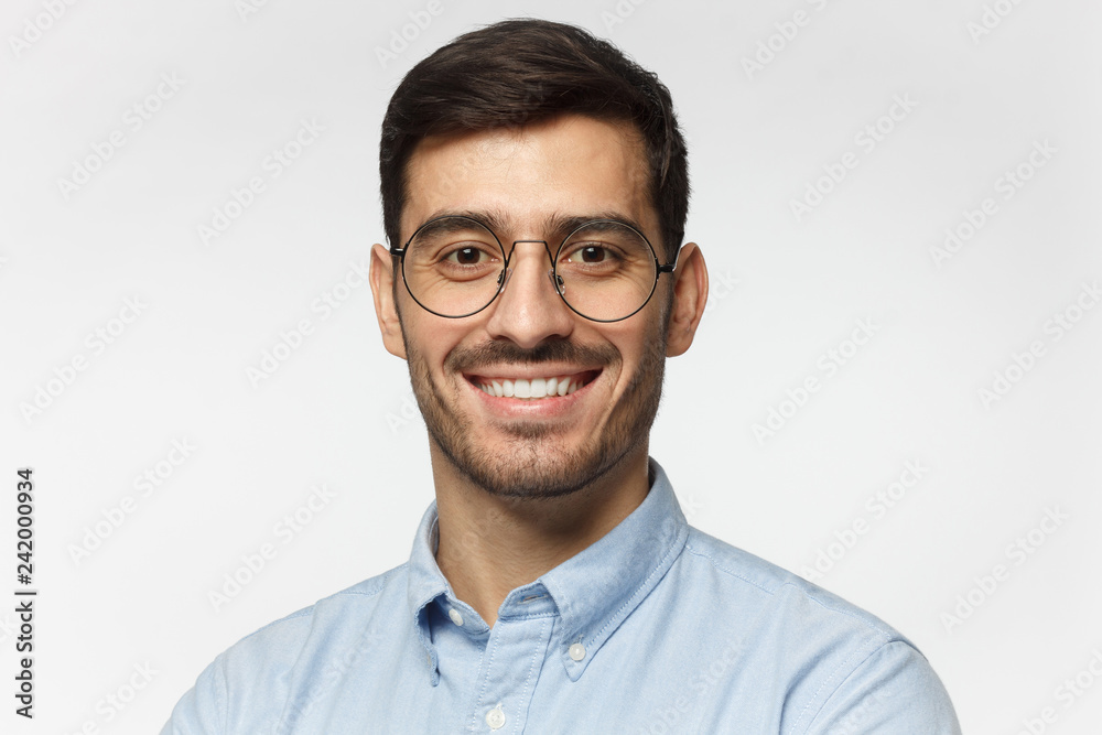 Smart businessman smiling at camera, wearing round glasses, isolated on gray background Smart businessman smiling at camera, wearing round glasses, isolated on gray background