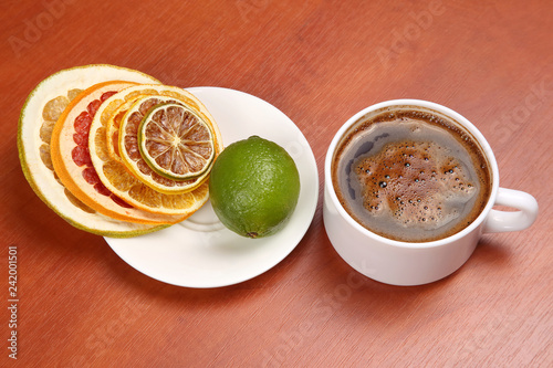 Dried slices of various citrus fruits and black coffee in a white Cup