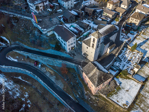 Arial view of village in swiss mountains in Ticino in winter with snow covered roofs