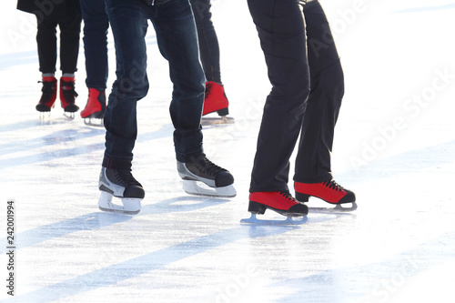 feet of different people skating on the ice rink © photosaint