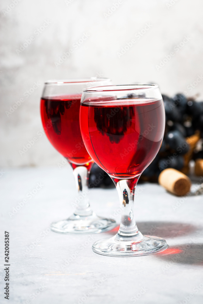 two glasses of red wine on a gray table