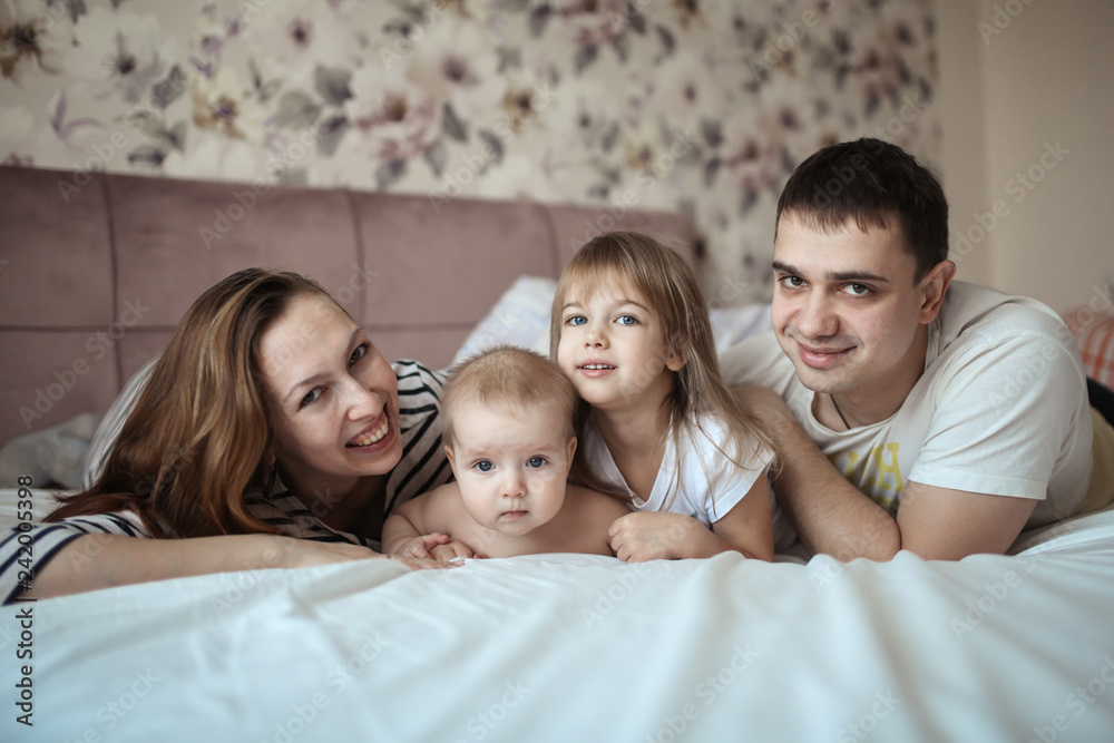 Funny family with two children in real room bed