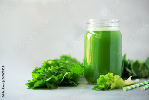 Bottle of green celery smoothie on grey concrete background. Banner with copy space. Square crop. Fresh juice for detox. Vegan, alkaline healthy diet concept
