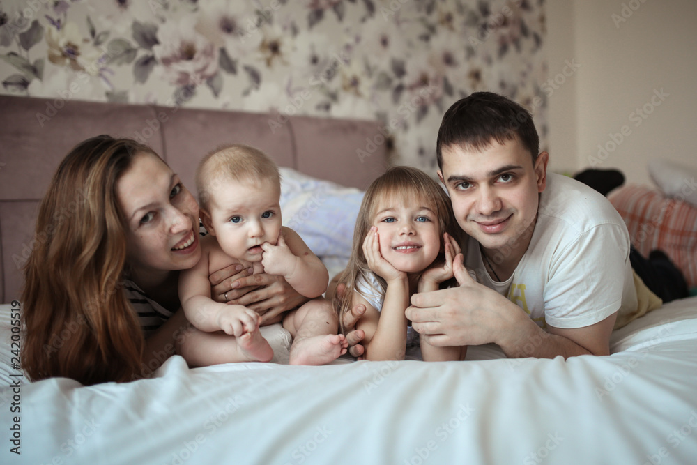 Funny family with two children in real room bed