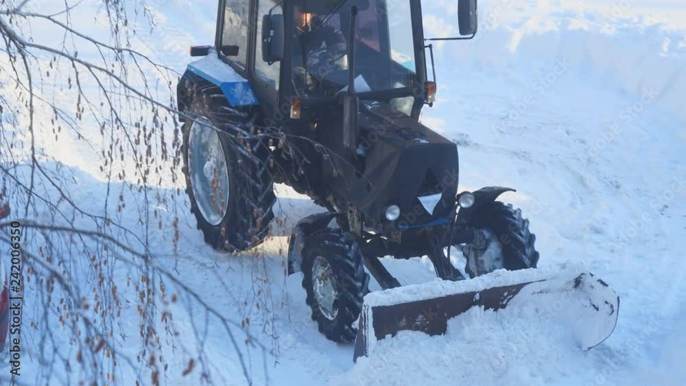 Snowplow on the street. A tractor clears snow from the road Snowplow on the street. A tractor clears snow from the road