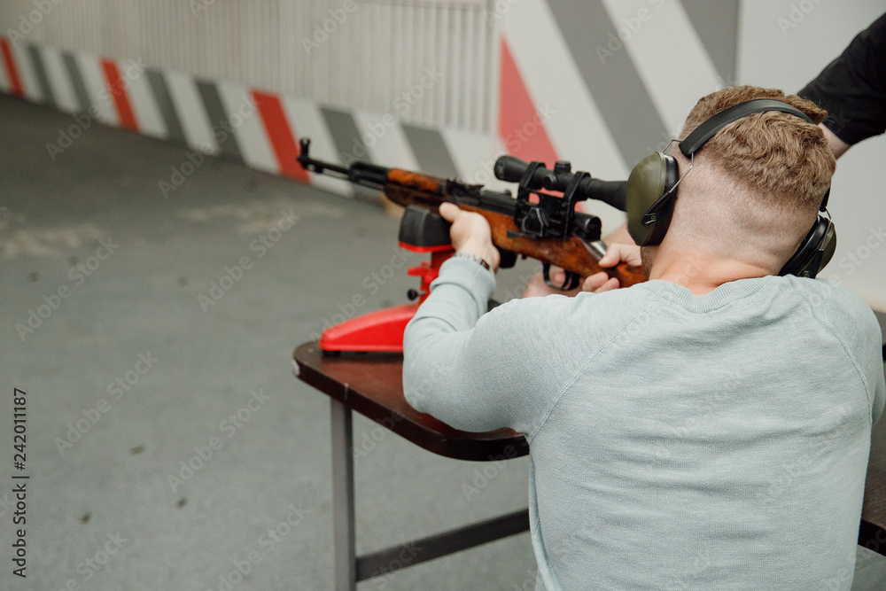 Shooting training. Man shoots from aim gun in paper target