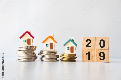 Miniature house on stack coins with wooden block year 2019 using as business and property concept