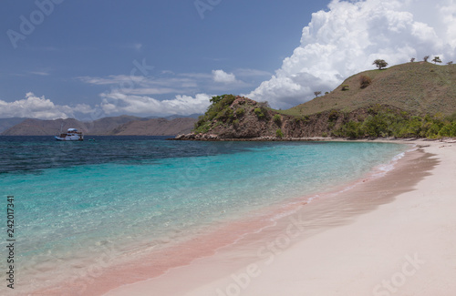Fototapeta Naklejka Na Ścianę i Meble -  Pink beach with crystal clear water and a boat near tropical islands