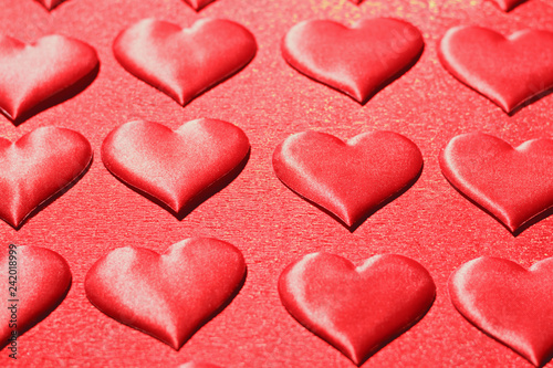 Closeup of a red heart on a shiny red background. The concept of love, choice and celebration of Valentine's Day. Selective focus.