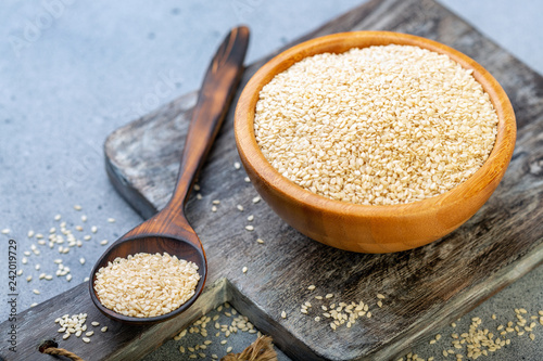 White sesame seeds in a wooden bowl and spoon.