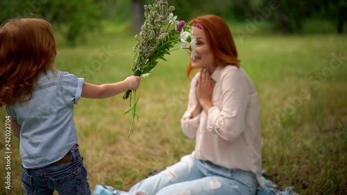 Beautiful kid gives flowers to smiling mother