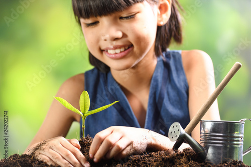 A girl planting young plant on soil with a hope of good environment