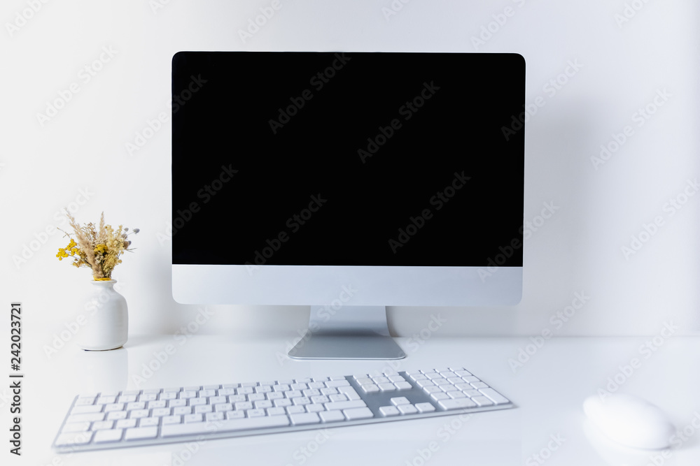 Clean and minimalistic office working place with desktop computer. Front view of PC, cell phone, papers and numeric keyboard on clean white table Clean and minimalistic office working place with desktop computer. Front view of PC, cell phone, papers and numeric keyboard on clean white table