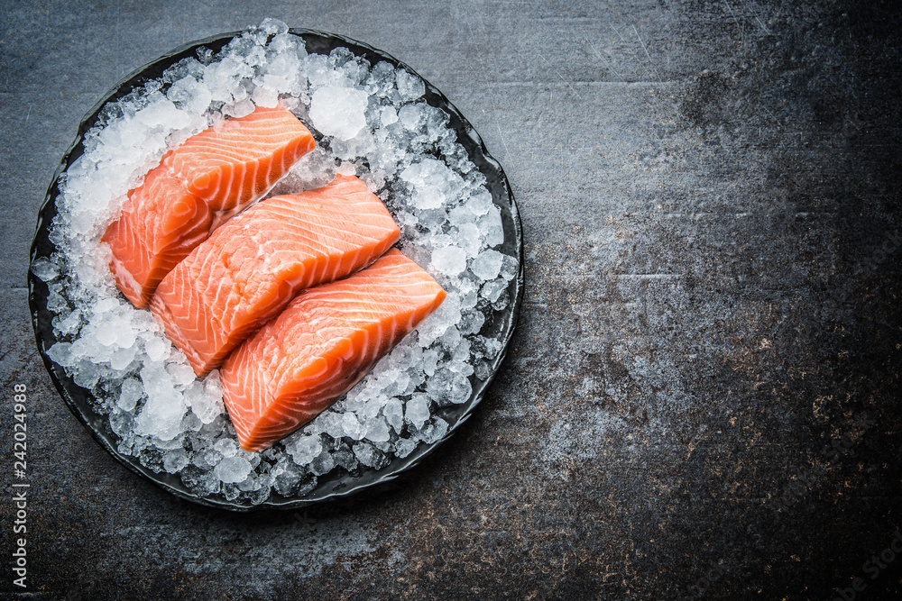 Obraz na płótnie Portioned raw salmon fillets in ice on plate - Top of view