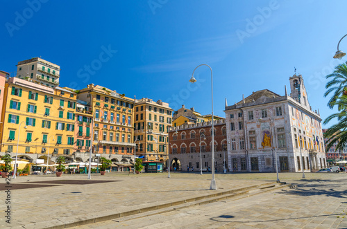 Row of colorful buildings and Palazzo San Giorgio palace on Piazza Caricamento square near harbor in historical centre of old european city Genoa Genova with blue sky background, Liguria, Italy