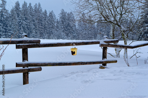 Scenic view of the winter landscape and an yellow bucket hanging on the railing