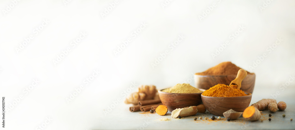 Ingredients for hot ayurvedic drink. Turmeric powder, curcuma root, cinnamon, ginger, lemon over grey background. Copy space, square crop. Spices for alternative medicine - obrazy, fototapety, plakaty 