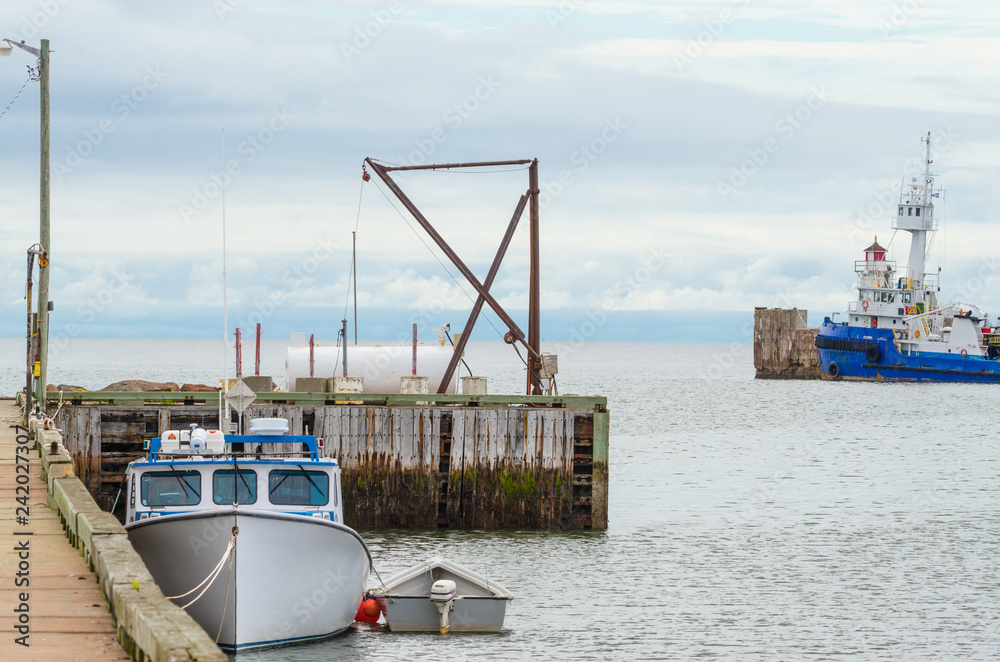 Φωτογραφία Tug boat and a fishing boat, idle for the day, no people around, hot summer day on a wharf in a New Brunswick harbour
