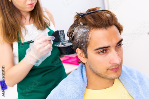 Woman hairdresser applying dye to man hair