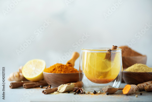 Ingredients for turmeric hot tea on grey background. Healthy ayurvedic drink with lemon, ginger, cinnamon, turmeric. Immune boosting remedy