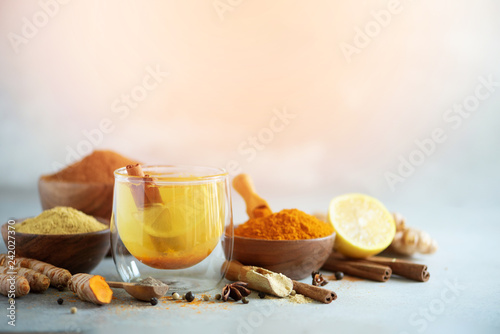 Ingredients for turmeric hot tea on grey background. Healthy ayurvedic drink with lemon, ginger, cinnamon, turmeric. Immune boosting remedy