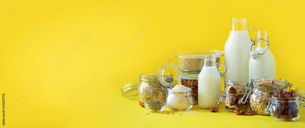 Φωτογραφία Glass bottles of vegan plant milk and almonds, nuts, coconut, hemp seed milk on yellow background