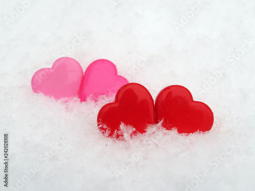 Valentine hearts in the snow, red and pink symbols of love. Background for romantic greeting card with free copy space