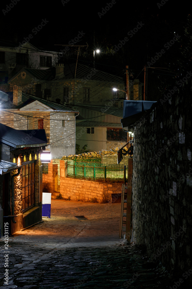 A paved path in a traditional Nimfeo village in Macedonia in Greece. The enlightened shops and lighted streets are visible. A paved path in a traditional Nimfeo village in Macedonia in Greece. The enlightened shops and lighted streets are visible.