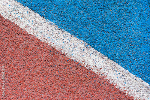 Abstract view on a red - blue synthetic tartan track surface of athletics stadium with white diagonal line  as texture, background photo