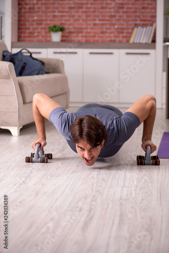 Young handsome man doing sport exercises at home 