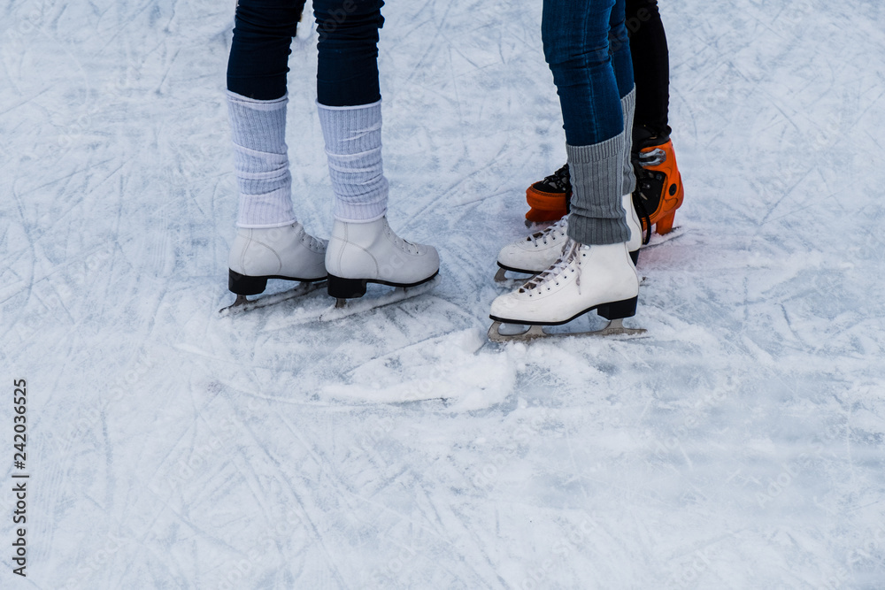 Legs of a three women with ice skating shoes on ice Legs of a three women with ice skating shoes on ice