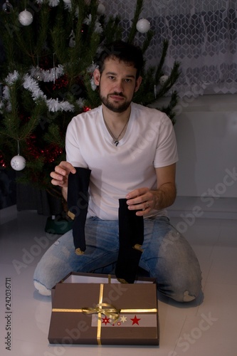 The young man got a improper  Christmassy gift.The man got socks as a gift. He is disappointed.Returning goods after Christmas.