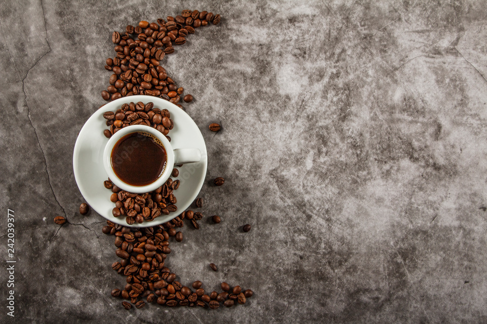 White cup with black coffee and grains of coffee on a background of gray stone. View from above. Place for text. White cup with black coffee and grains of coffee on a background of gray stone. View from above. Place for text.