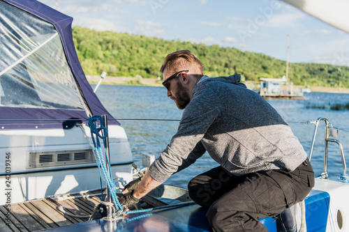 Young man lifting the sail of catamaran during cruising photo