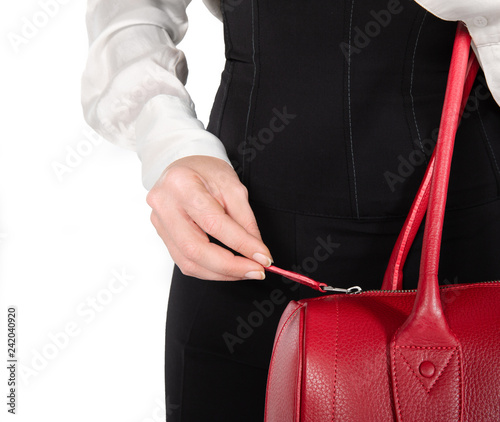 elegantes weibliches Model mit weißerBluse, schwarzer Hose öffnet den Reißverschluss ihrer roten Lederhandtasche, Studioshooting, weißer Hintergrund, close up photo