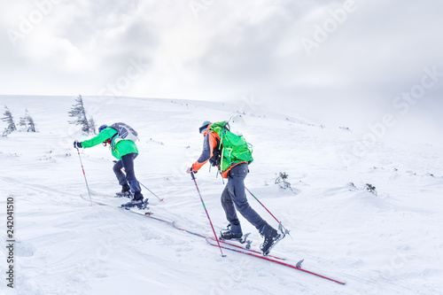 Two ski sportsmen going up to the summit in snowy mountains. Skitouring sport concept.