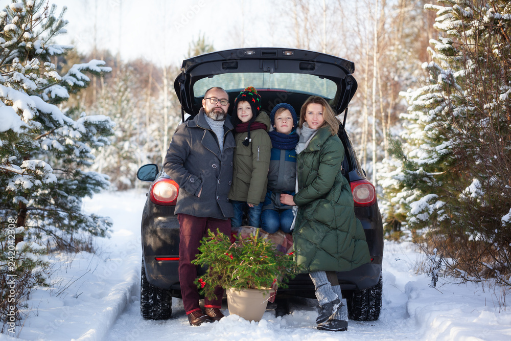 Happy family near black car at snowly winter day. Concept holiday vacation.