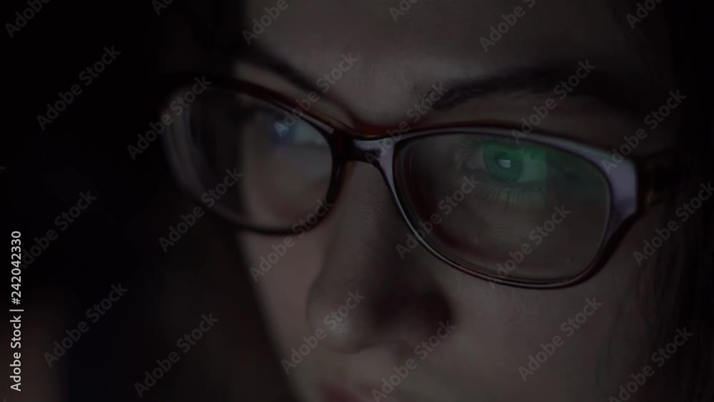 Young attractive girl in glasses is using a laptop while lying on the bed. Night shooting Young attractive girl in glasses is using a laptop while lying on the bed. Night shooting