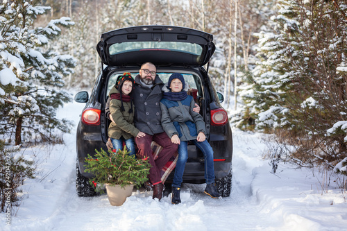 Happy family near black car at snowly winter day. Concept holiday vacation.