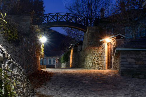 Traditional stone-built houses in the village of Nymfaio. There is a small bridge in the background. Night photo photo