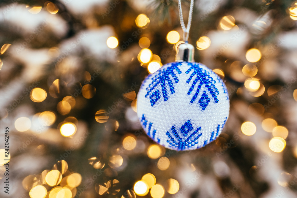 Fototapeta premium Blue white christmas ball on fir tree branch close up golden yellow light bokeh background